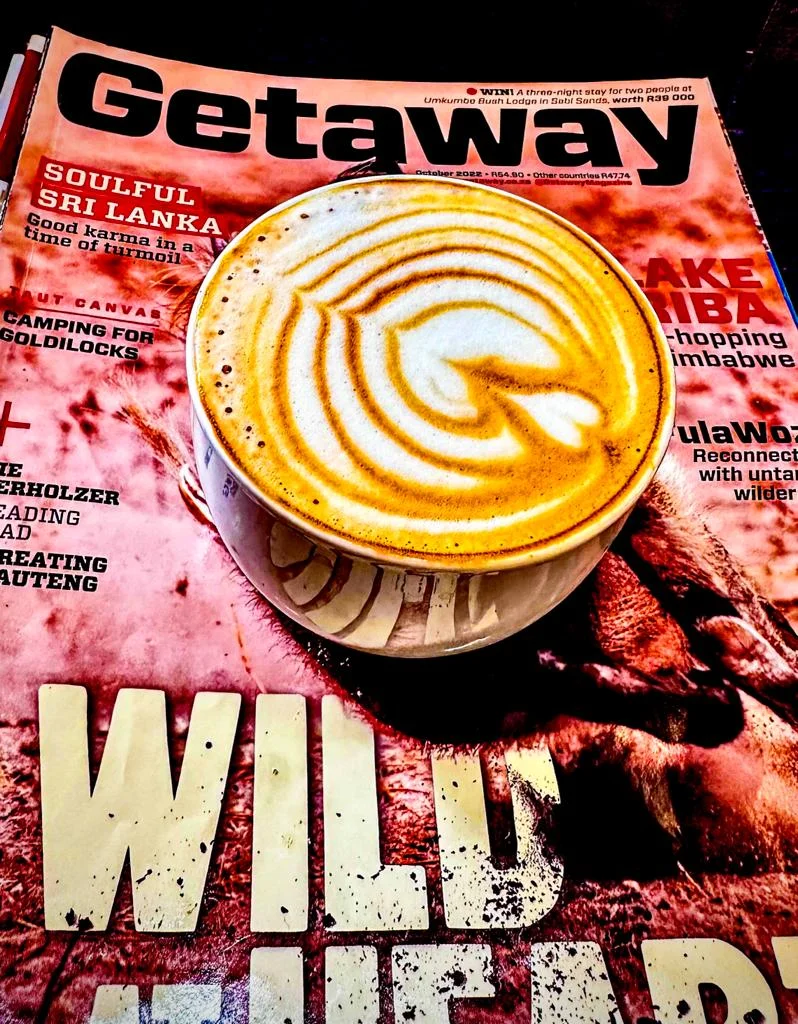 Latte resting on a travel magazine on a café table