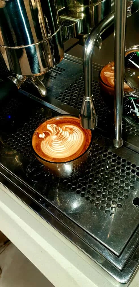 Latte poured fresh on the espresso machine drip tray