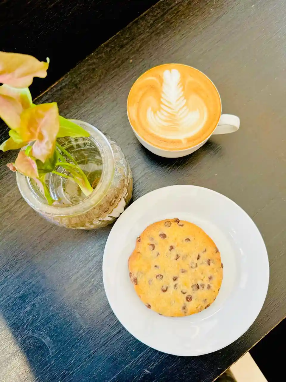 Latte alongside a fresh chocolate chip cookie