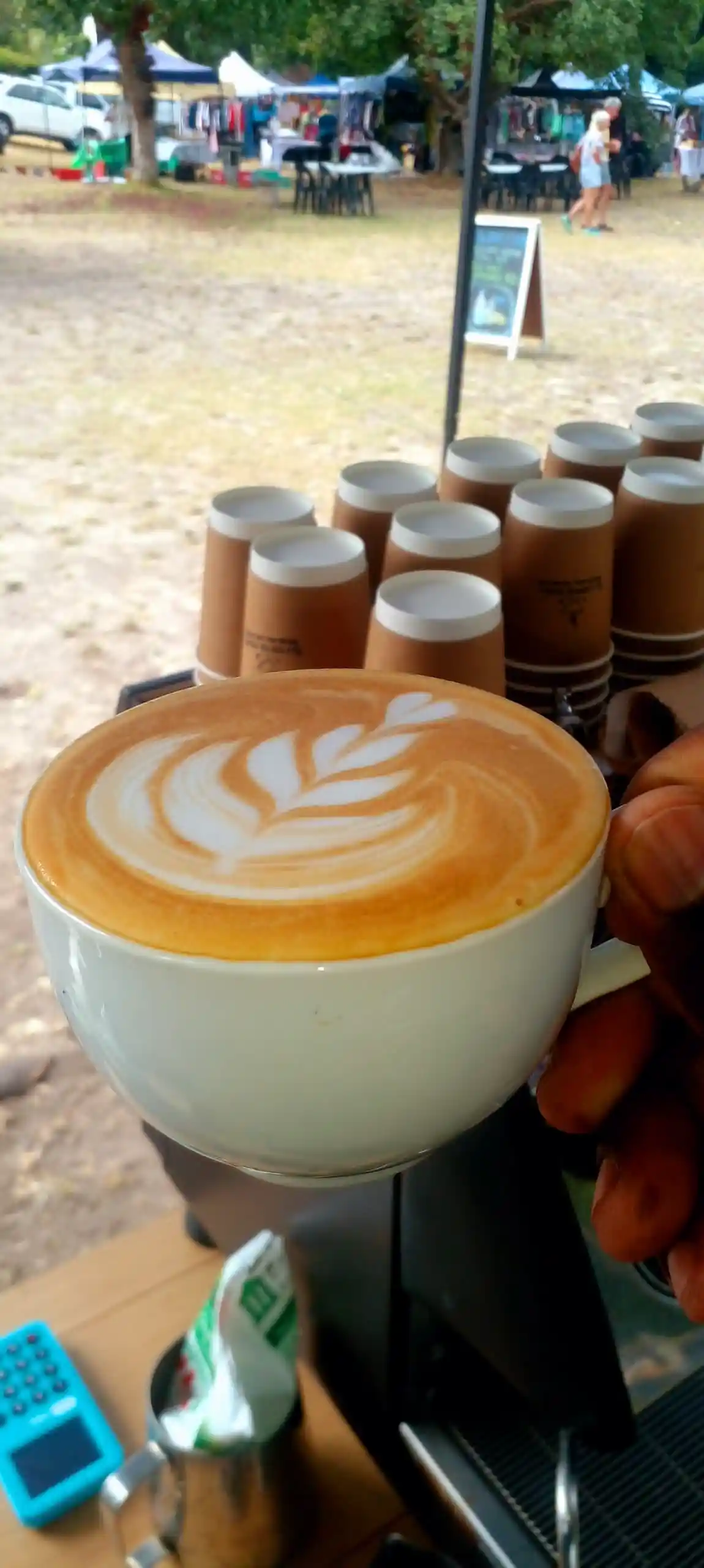 EL-J Coffee latte held up at an open-air market