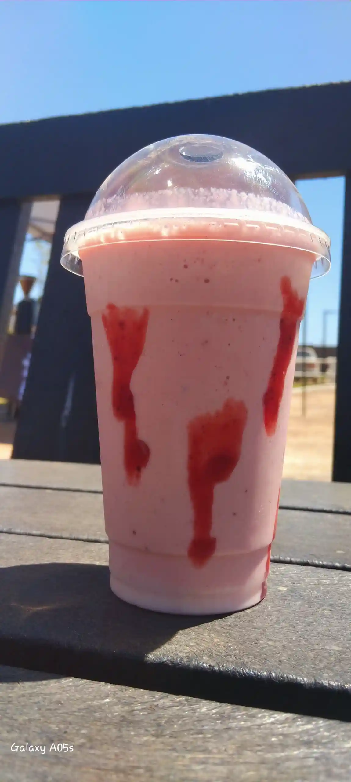Strawberry frappé with dome lid against a clear blue sky