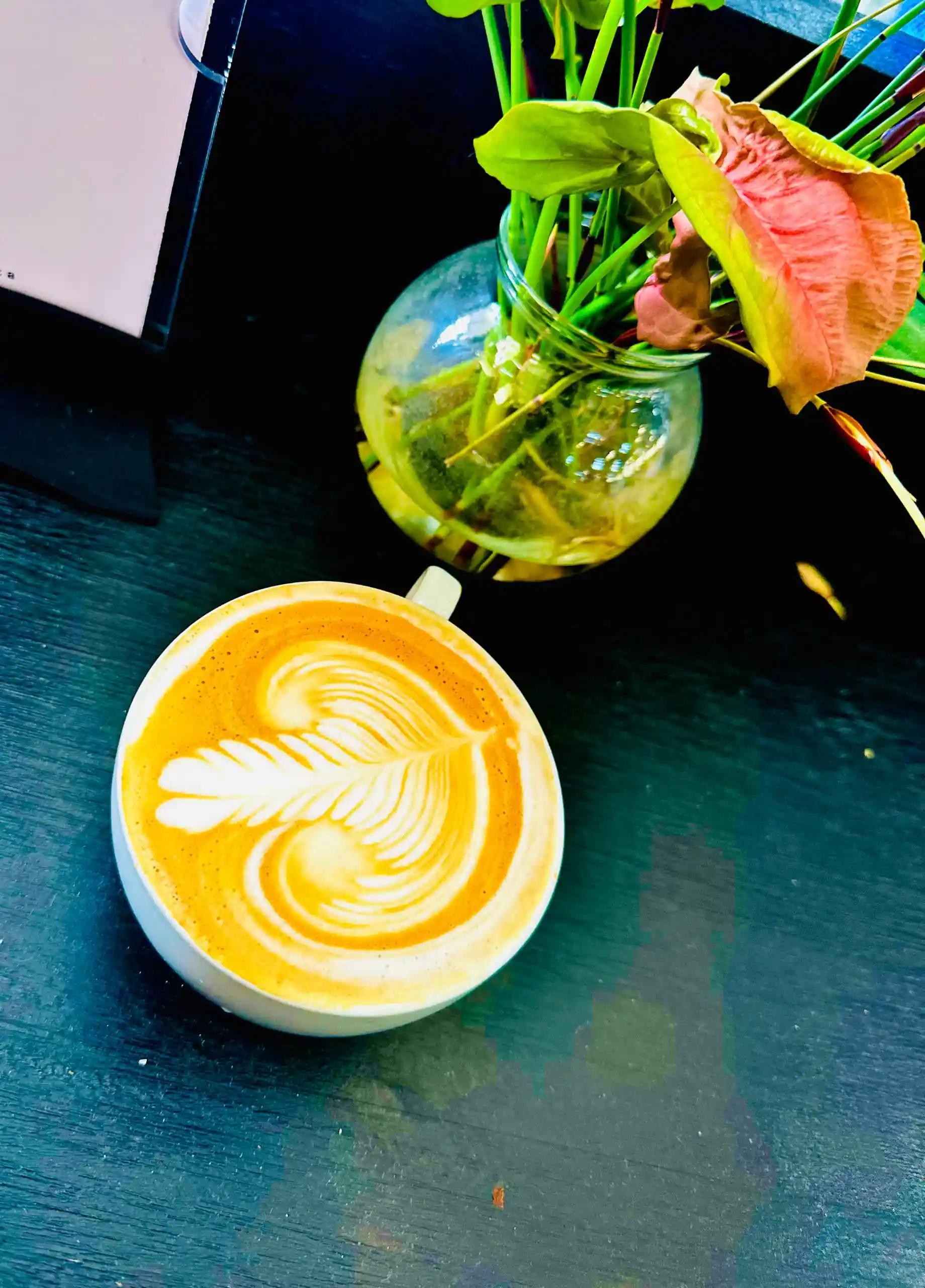 Vibrant latte art in a bright setting with tropical foliage