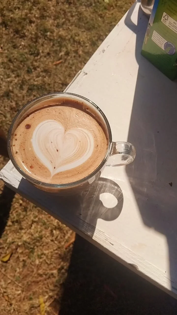 Heart latte art in a clear glass mug on an outdoor table